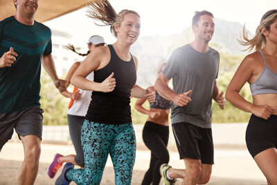 Group of happy young friends running together. Running club members exercising.